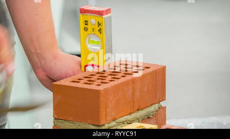 Aligning the bricks using the ruler with the cement as a paste to make the bricks stick together Stock Photo