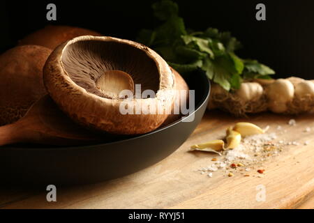 Fresh raw portobello mushrooms in pan on wooden table Stock Photo