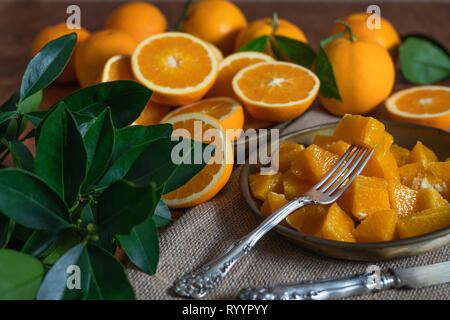 Oranges sliced and  orange leaves on a kitchen table with rustic background Stock Photo