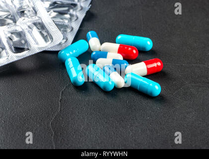 Scattered multicolored capsules with blister on a dark background Stock Photo