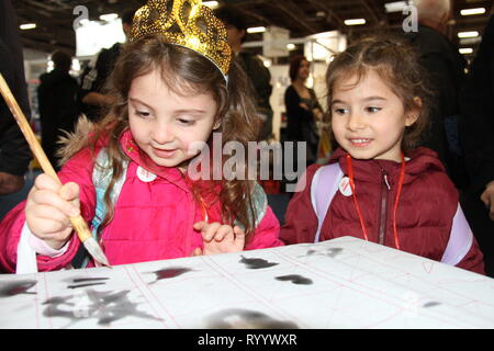 Paris, France. 15th Mar, 2019. A little girl tries Chinese calligraphy at the Chinese exhibition area of the 2019 Paris book fair in Paris, capital of France, on March 15, 2019. Credit: Yang Yimiao/Xinhua/Alamy Live News Stock Photo