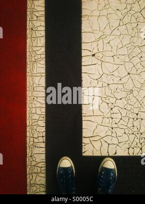 Looking down at feet on cracked painted surface Stock Photo