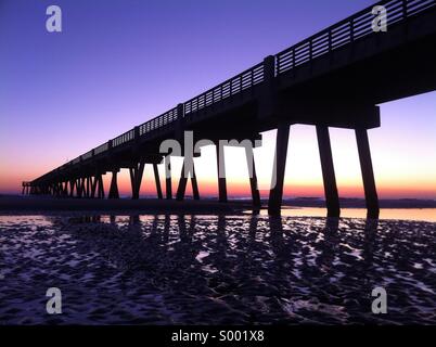 The brilliant colors of sunrise bathe an early morning view of Jacksonville Beach Pier in North Florida. USA. Stock Photo