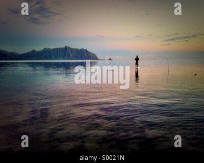 Stand up board fishing at Kaneohe Bay, Oahu, Hawaii. Kualoa Koolau mountains as backdrop. Stock Photo