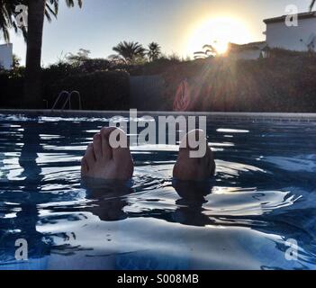 Feet sticking out from a swimming pool at a Spanish villa. Stock Photo