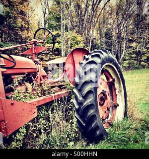 Old tractor with overgrown weeds. Stock Photo
