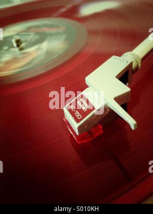 Red coloured vinyl record on a vintage record player Stock Photo