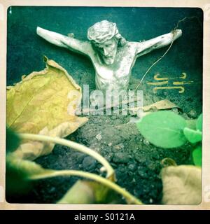 A sculpture of Jesus Christ crucified missing his hands decorates a tomb full of tree leaves during Day of the Dead celebrations in Teotitlan del Valle, Oaxaca, Mexico Stock Photo