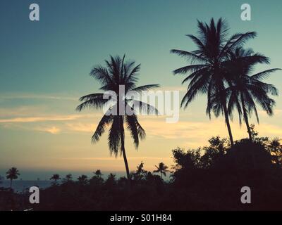 Sunset over Ao Nang Beach, Krabi, Thailand, with islands in the distance and palm tree silhouettes. Stock Photo