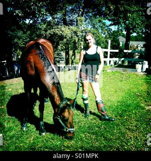Teenage girl with her horse eating grass Stock Photo