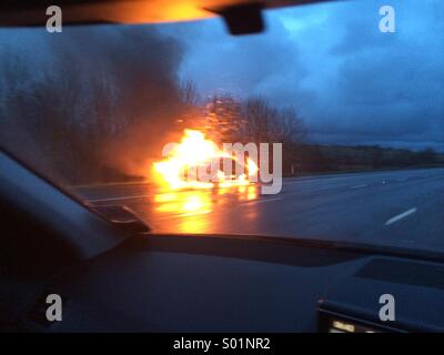 Car on fire on hard shoulder of motorway Stock Photo