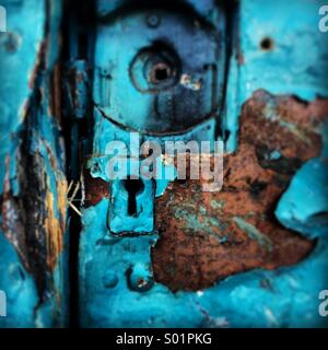 Rusty old run-down painted blue door with broken lock. Stock Photo