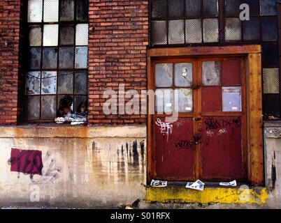 Windows and the door on a brick building are haphazardly painted over and run down Stock Photo