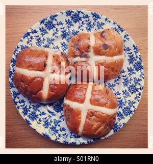 Three hot cross buns in a vintage blue and white floral plate Stock Photo