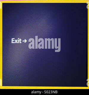 An exit sign on a blue wall Stock Photo