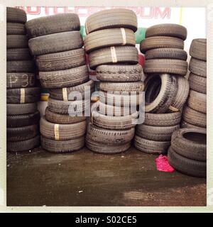 Old tires stacked against a wall are seen. Stock Photo