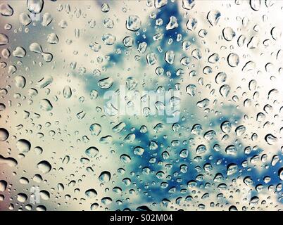 Large water drops in car windshield, out of focus clouds and sky in background. Stock Photo