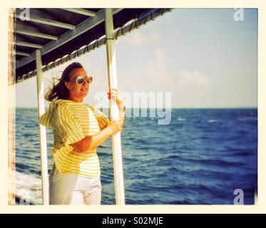 Beautiful woman standing on a boat during her vacation to the Maldives. Stock Photo