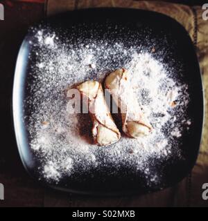 Two cannoli on a black plate Stock Photo