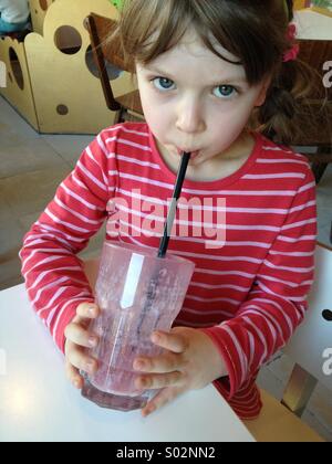 Little girl drinking fruit milk-shake with a straw Stock Photo