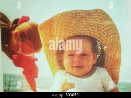 Baby aged 3-6 months with straw hat at the beach Stock Photo