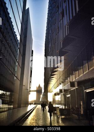 Commuters make their way along More London towards Tower Bridge which is framed between office buildings Stock Photo