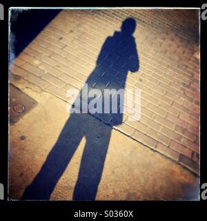 Shadow of person on pavement sidewalk Stock Photo