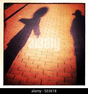 Mood shadows of two persons walking on pavement sidewalk Stock Photo