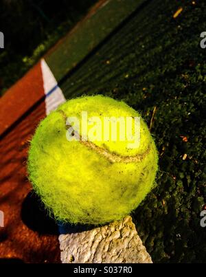 Tennis ball on sideline of court with shadow of net Stock Photo