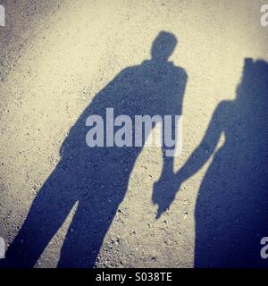 Shadow of couple holding hands, while walking down a road. Stock Photo