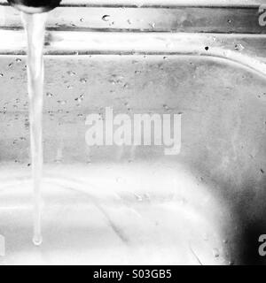 Tap running into 1970's stainless steel sink Stock Photo