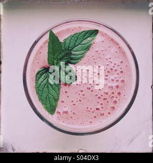 A strawberry smoothie with mint leaves is seen. Stock Photo