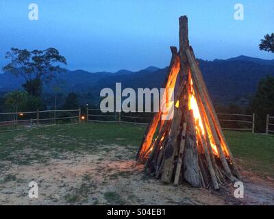 A wood Bonfire starting up in a fenced campsite Stock Photo