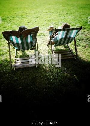 A couple lounging in deckchairs at a park on a sunny day Stock Photo