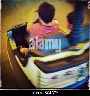 Two boys driving a bumper car in a fairground atraction