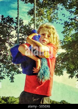 Young boy on a homemade swing in a park Stock Photo