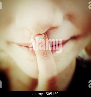 Young girl with single finger on her lips Stock Photo
