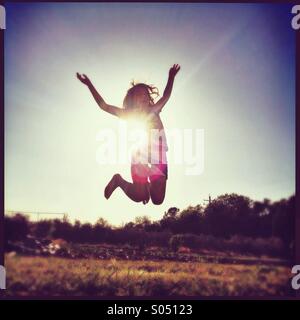 Girl jumping with sun at her back. Stock Photo