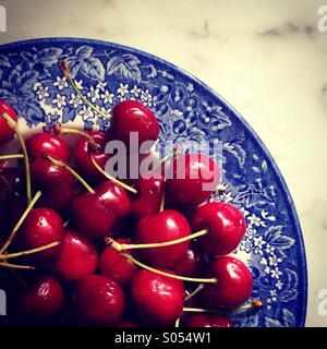 Red cherries in blue bowl. Stock Photo