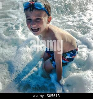 A boy playing in waves on Sant Pol de Mar beach, el Maresme coast, Barcelona, Spain Stock Photo