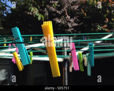 Colourful plastic clothes pegs on a washing line Stock Photo