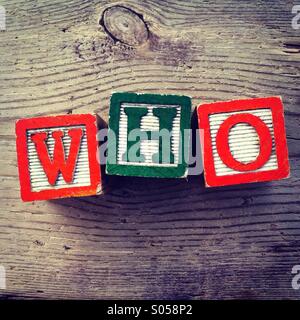 It's a photo of two wood cubes toy with letters that form the word WHO Stock Photo