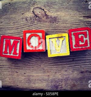 It's a photo of two wood cubes toy with letters that form the word MOVE Stock Photo