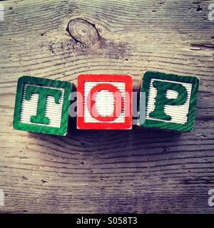 It's a photo of 3 wood cubes toy with letters that form the word TOP Stock Photo