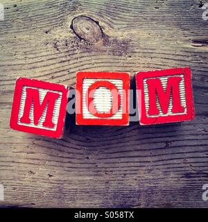 It's a photo of two wood cubes toy with letters that form the word MOM Stock Photo