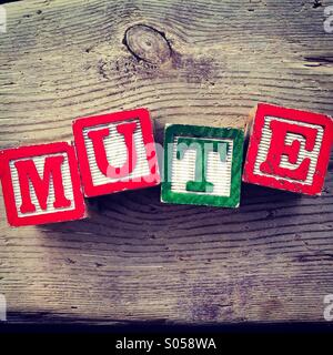 It's a photo of 4 wood cubes toy with letters that form the word MUTE Stock Photo