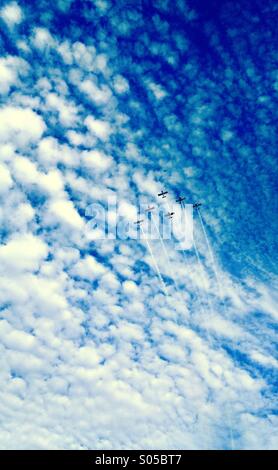 A group of airplanes flies in formation against a summer sky. Stock Photo