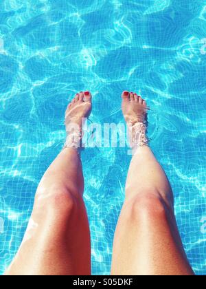 Dangling legs in swimming pool Stock Photo