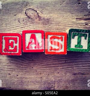 It's a photo of few wood blocks with alphabet letters on them that ate combined together to create the word EAST Stock Photo