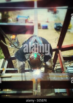 A steel worker welds a beam on a construction site for a new office building Stock Photo